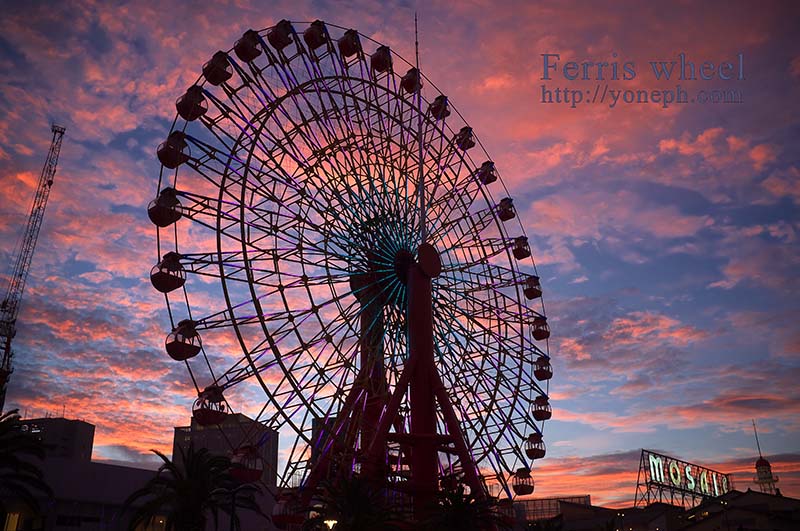 神戸のハーバーランドの観覧車の画像、日没間近の空、夕日で紅い雲と青い空を背景に観覧車がシルエットで描写